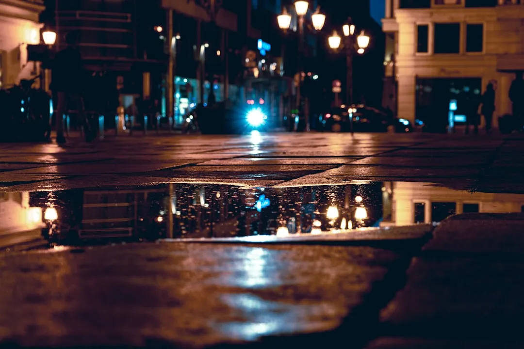 City street lights reflected in a puddle at night.