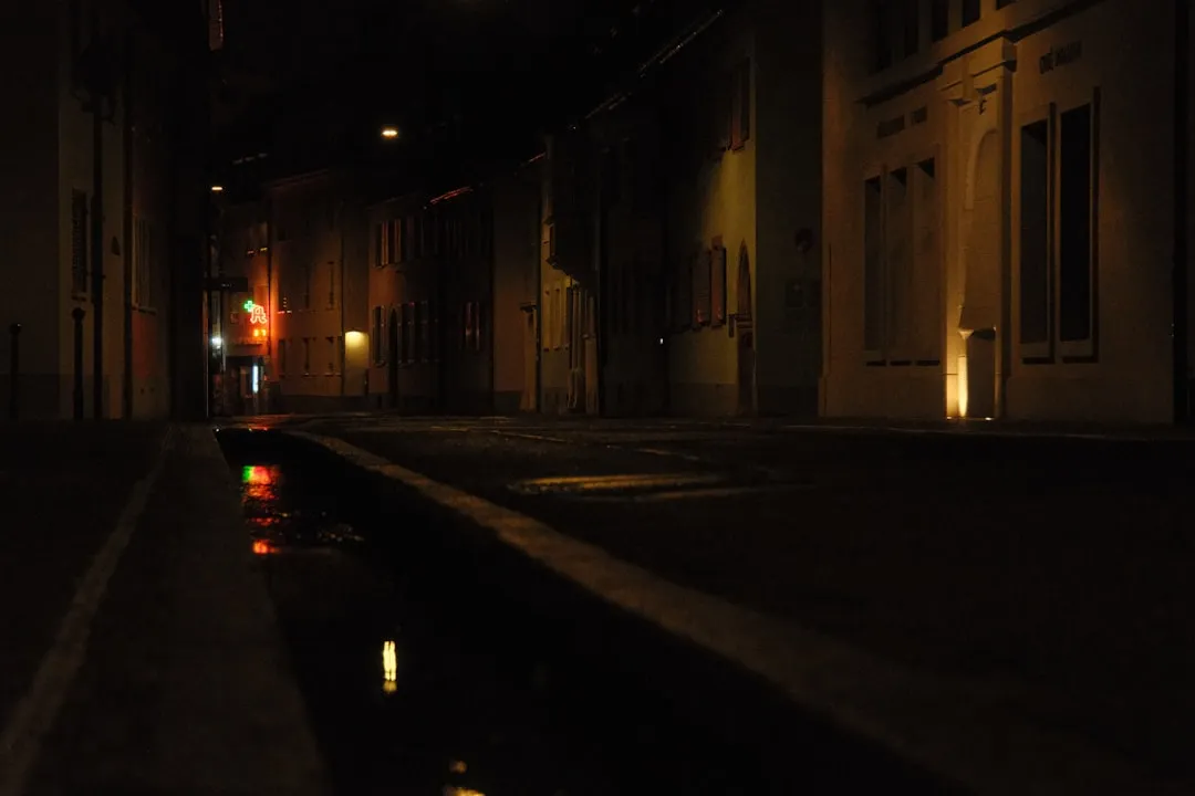 a dark street at night with a red traffic light
