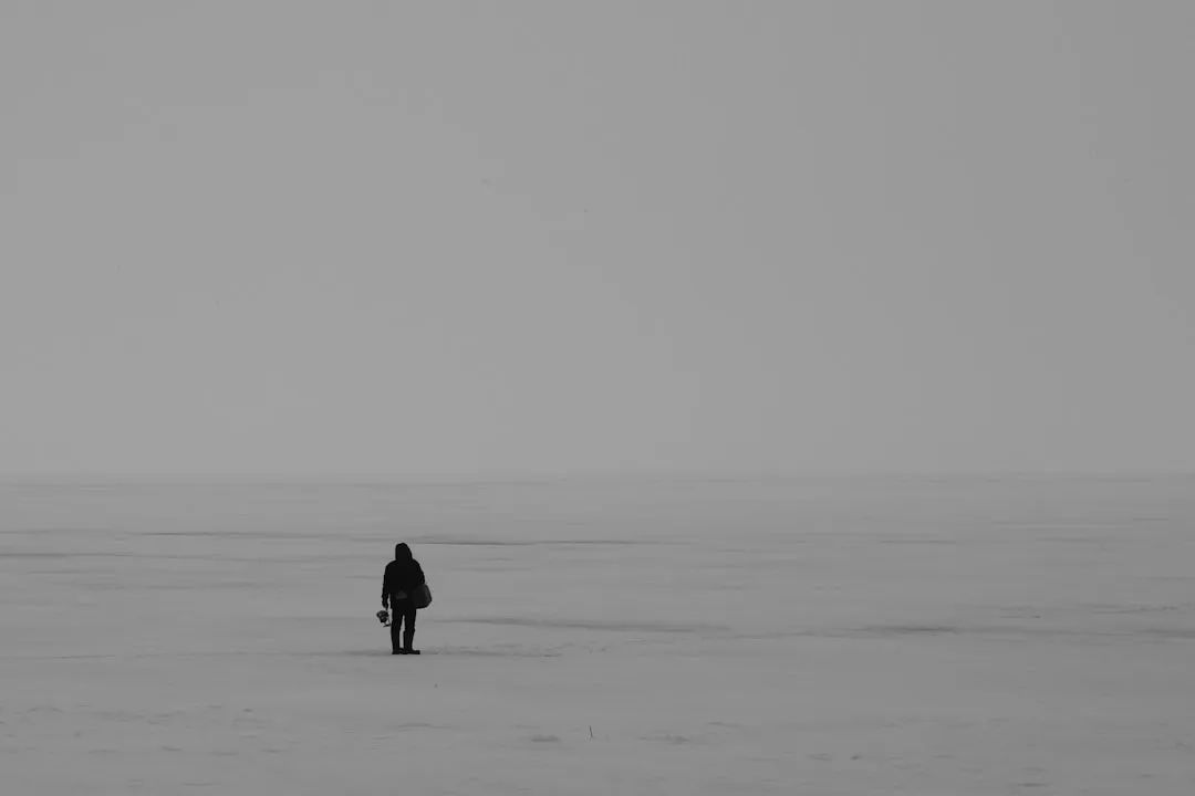 person in black jacket walking on snow covered field during daytime