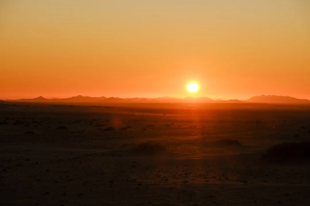 The sun is setting in the distance over the desert