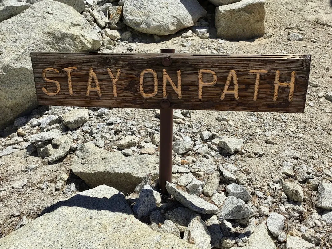 brown wooden signage on gray rocky ground during daytime