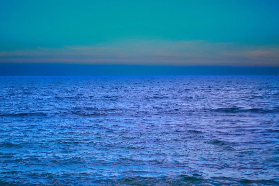 a large body of water with a sky in the background