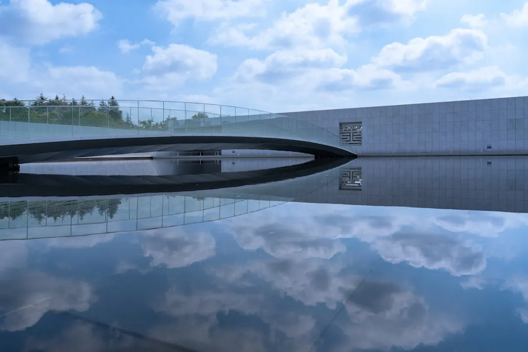 Modern bridge reflecting in still water under sky