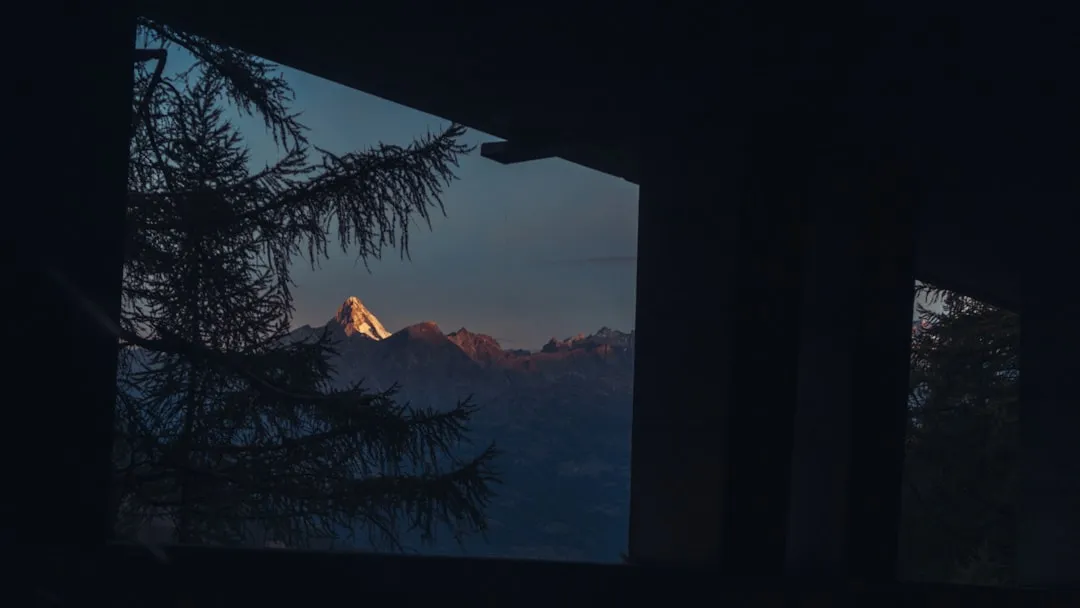 Mountain peak illuminated by sunrise viewed through window