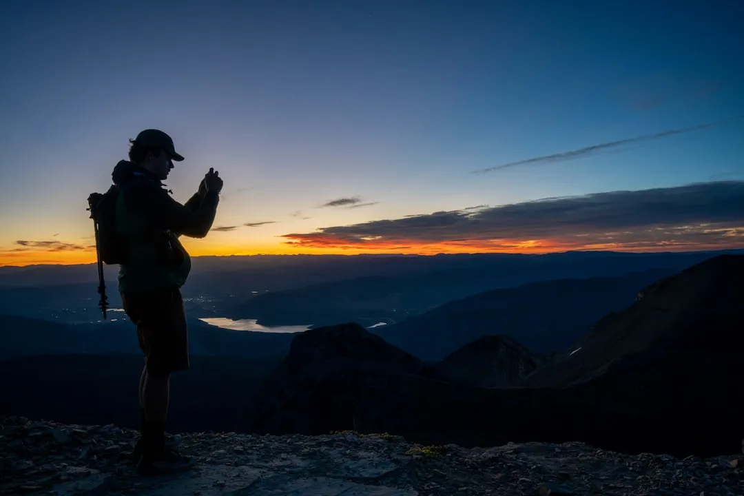 Man taking photo of sunset from mountain
