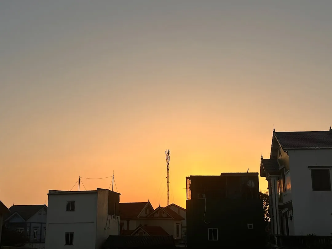 the sun is setting behind some houses