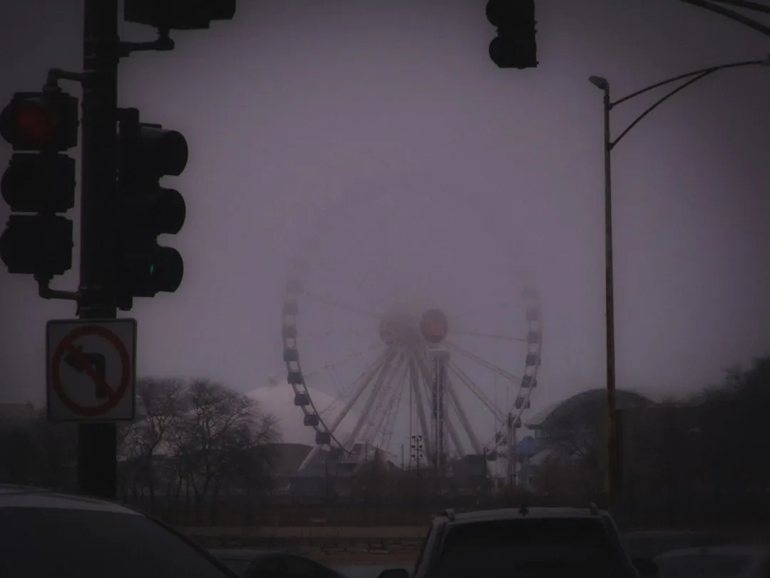 Ferris wheel obscured by thick fog on a gloomy day