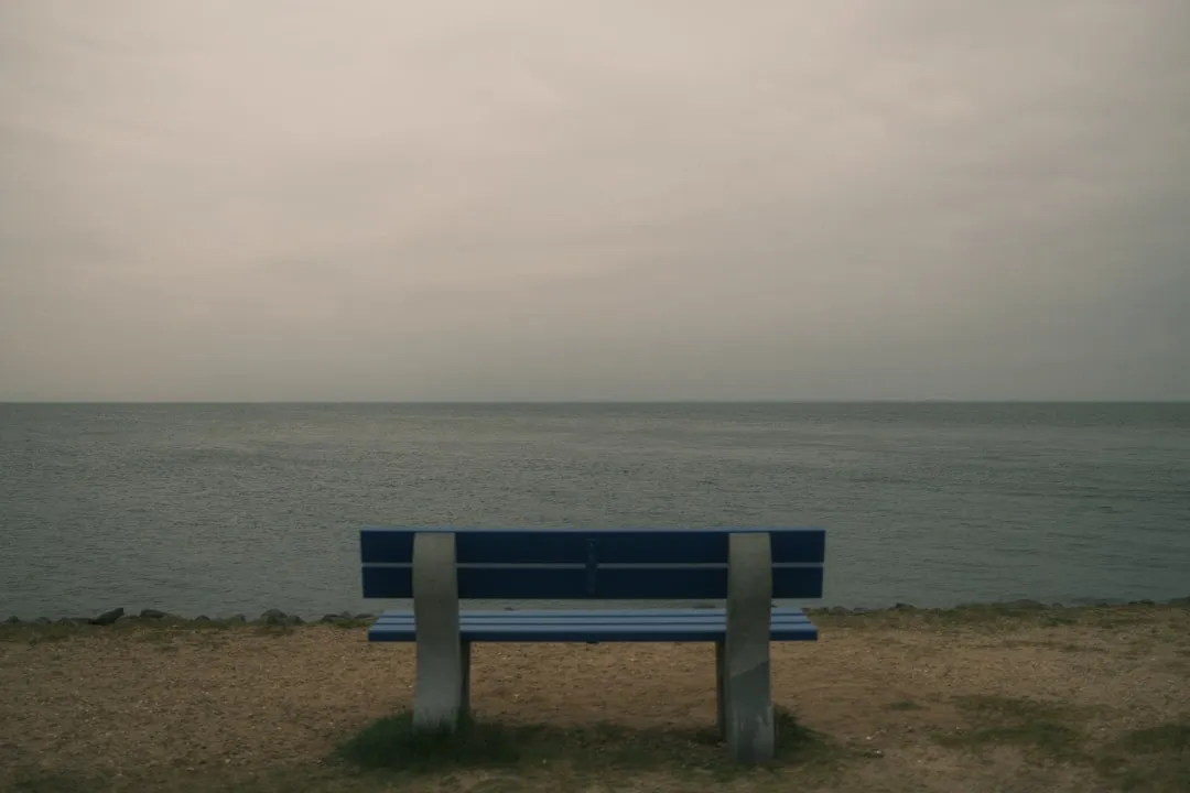 a blue bench sitting on top of a sandy beach