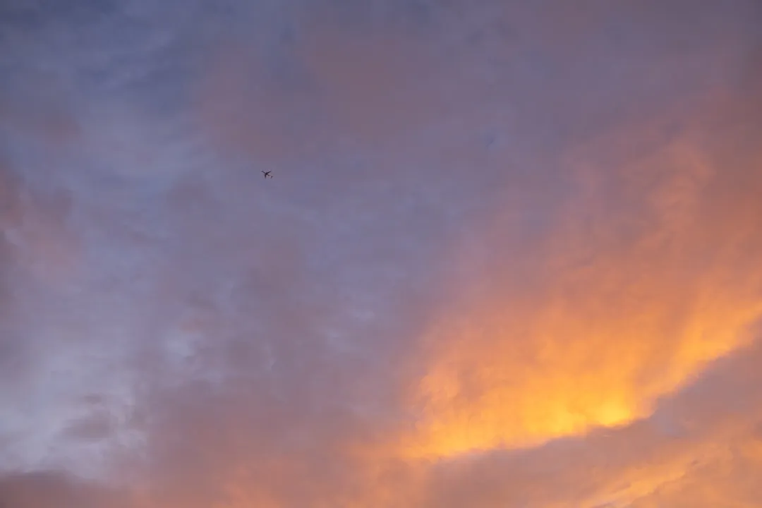 A plane flying in the sky with a sunset in the background